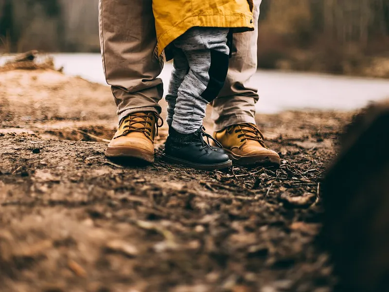Adult and child in hiking boots on a trail (illustrative photo)