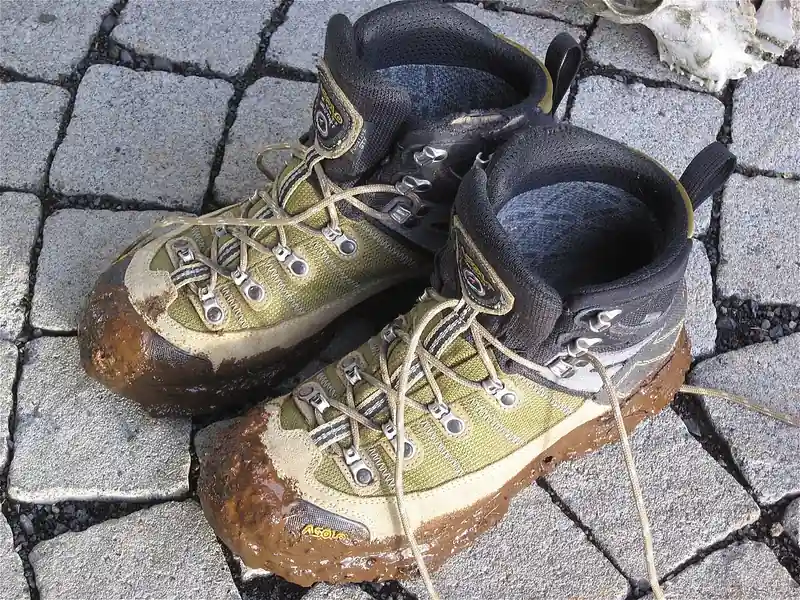 Muddy hiking boots on paving stones (illustrative photo)