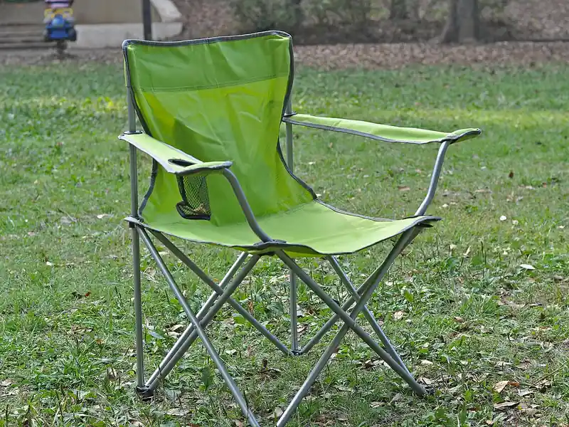 Green folding camp chair on grass (illustrative photo)