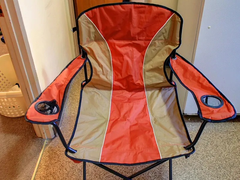 Red folding camp chair with armrests (illustrative photo)