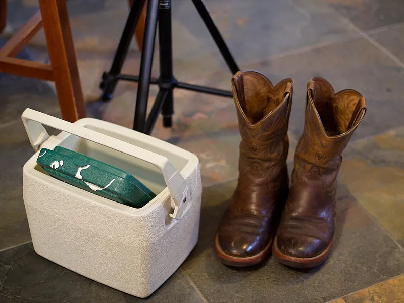 Small white cooler next to a pair of boots (illustrative photo)
