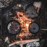Cast-iron pans on a grill over a campfire (illustrative photo)