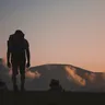 Hiker with a backpack silhouetted on a hilltop at dusk (illustrative photo)