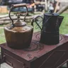 Copper kettle and coffee pot on a small outdoor stove (illustrative photo)