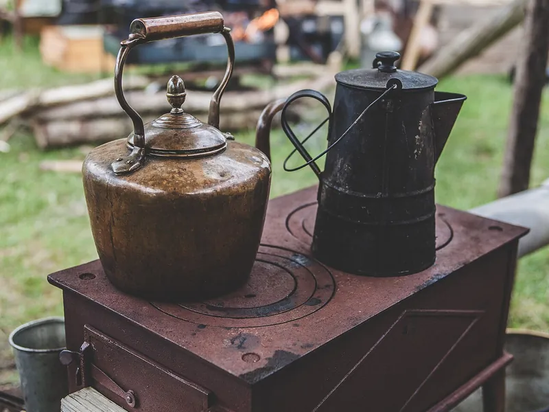 Copper kettle and coffee pot on a small outdoor stove (illustrative photo)