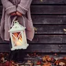 Person holding a white lantern with a candle (illustrative photo)