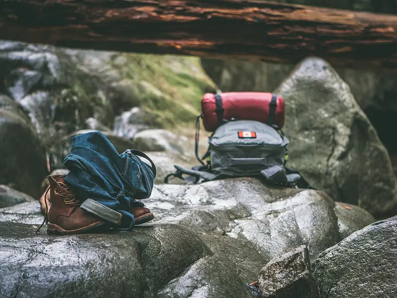 Hiking packs and a rolled sleeping bag on boulders (illustrative photo)