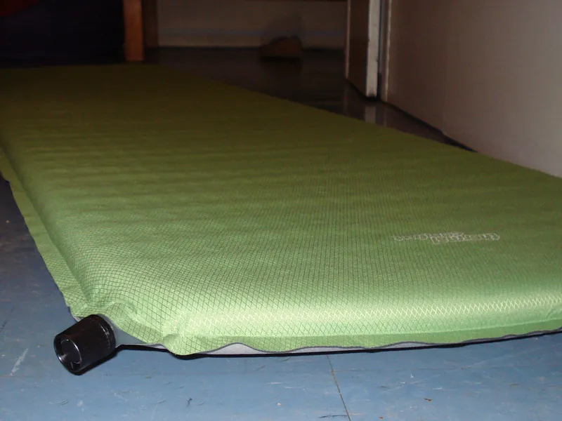 Green self-inflating sleeping pad on a floor (illustrative photo)