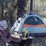 Dome tent with a camp chair at a forest campsite (illustrative photo)