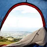 View out of a tent door past a sleeping bag to the hills (illustrative photo)