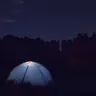 Dome tent glowing from inside at night (illustrative photo)