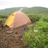 Orange dome tent on a grassy hillside (illustrative photo)