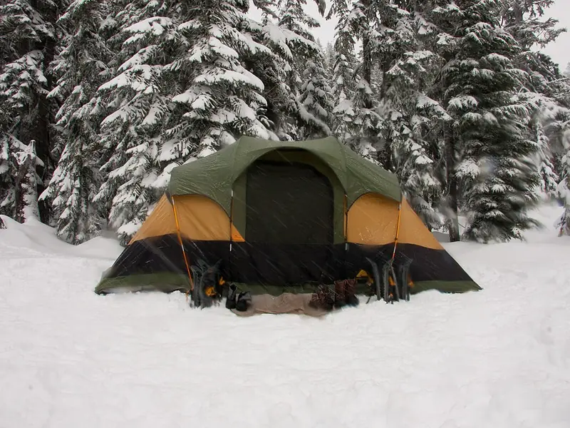 Family dome tent pitched in the snow among pines (illustrative photo)