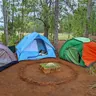 Three colorful dome tents around a campfire ring (illustrative photo)