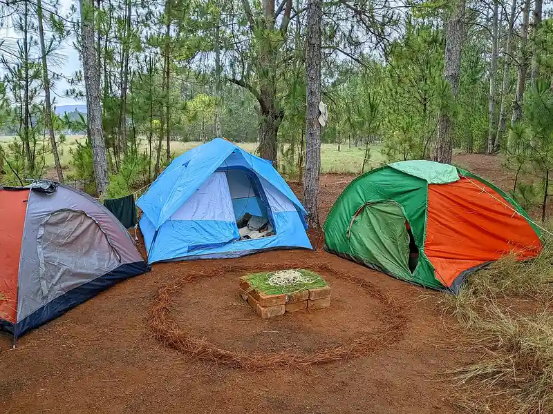 Three colorful dome tents around a campfire ring (illustrative photo)