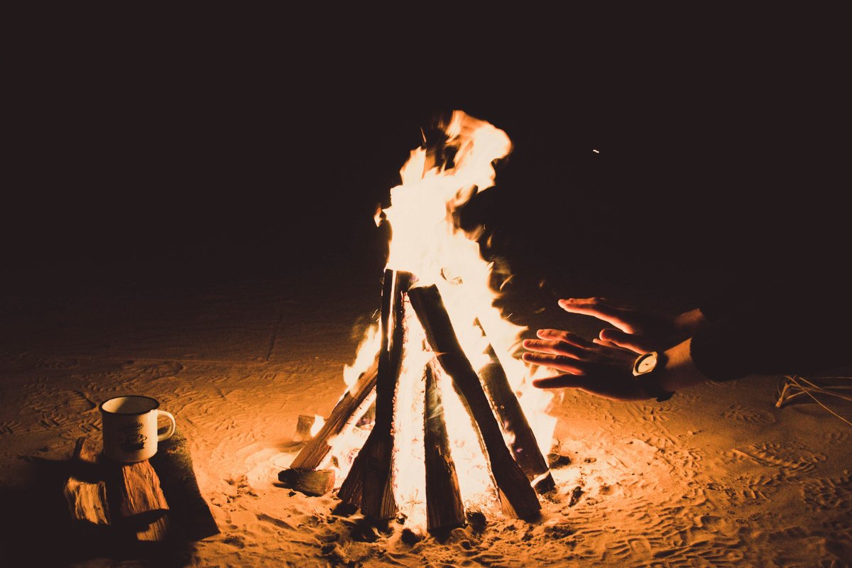 Log campfire burning at night inside a sandy fire pit