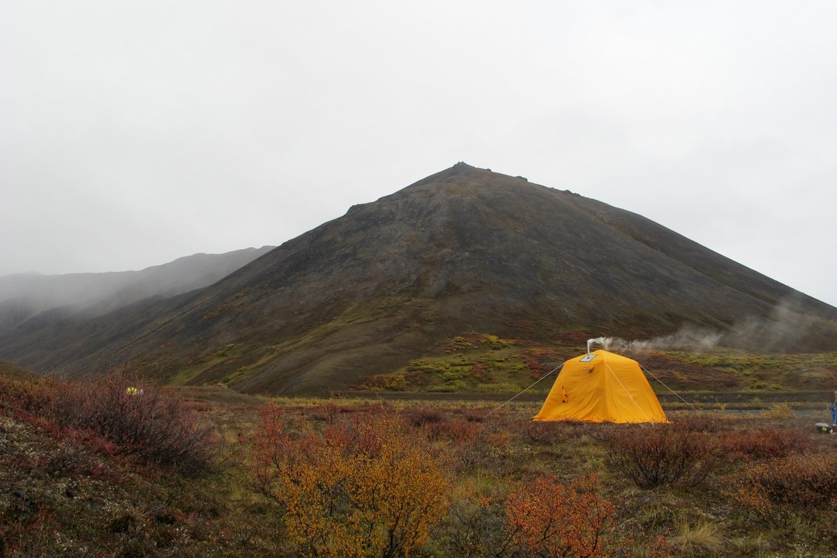 Orange tent on a rocky hillside at dusk