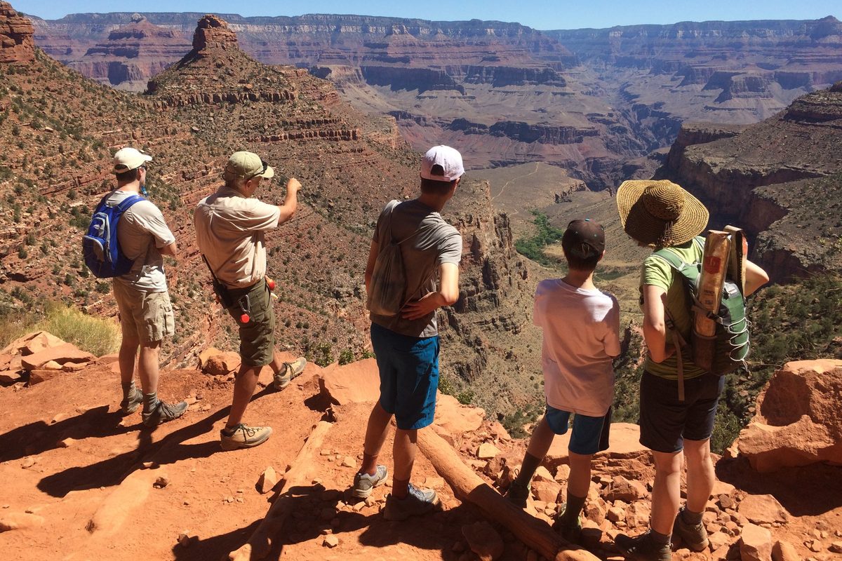 Illustrative photo of a park search-and-rescue volunteer talking with a group of hikers on a canyon trail